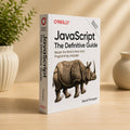 JavaScript: The Definitive Guide by David Flanagan – O'Reilly paperback showing front cover and spine in a lifestyle setting